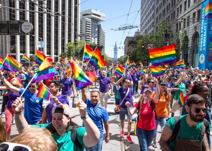 Borítókép: Fotó a San Franciscó-i Pride felvonulásról, tele szivárványszín-csíkos zászlókat lobogtató emberekkel.