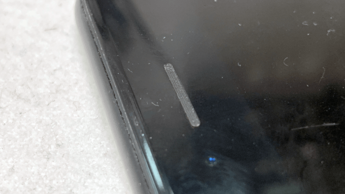 Borítókép – egy teljesen eltömődött hangszórórács egy iPhone 7 esetén