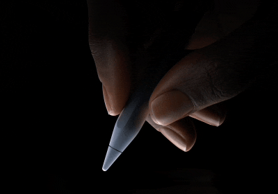 Egy felhasználó írásra kész helyzetben tartja hüvelyk- és mutatóujja között az Apple Pencil Prót a szár alsó harmadánál fogva. A felhasználó megnyomja az Apple Pencil Prót, aminek hatására kék fény villan, a felhasználó által érzékelt fizikai visszajelzést jelképezve.