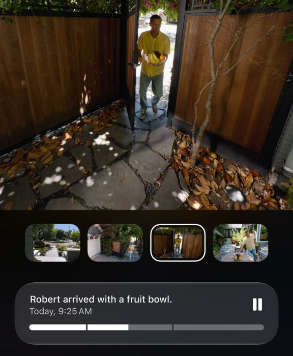 A HomeKit videókamerák képernyőképei láthatók, amelyeken egy személy belép egy elkerített hátsó udvarba. A mesterséges intelligencia által generált leírás: „Robert egy gyümölcstállal érkezett”, „Ma, 9:25”.