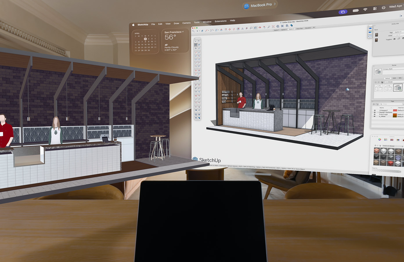 Az Apple Vision Pro nézete látható, amelyben egy MacBook Pro egy felületen helyezkedik el, mögötte pedig 3D modellek jelennek meg. A modellek egy kávézópultot ábrázolnak, amely mögött két ember áll.