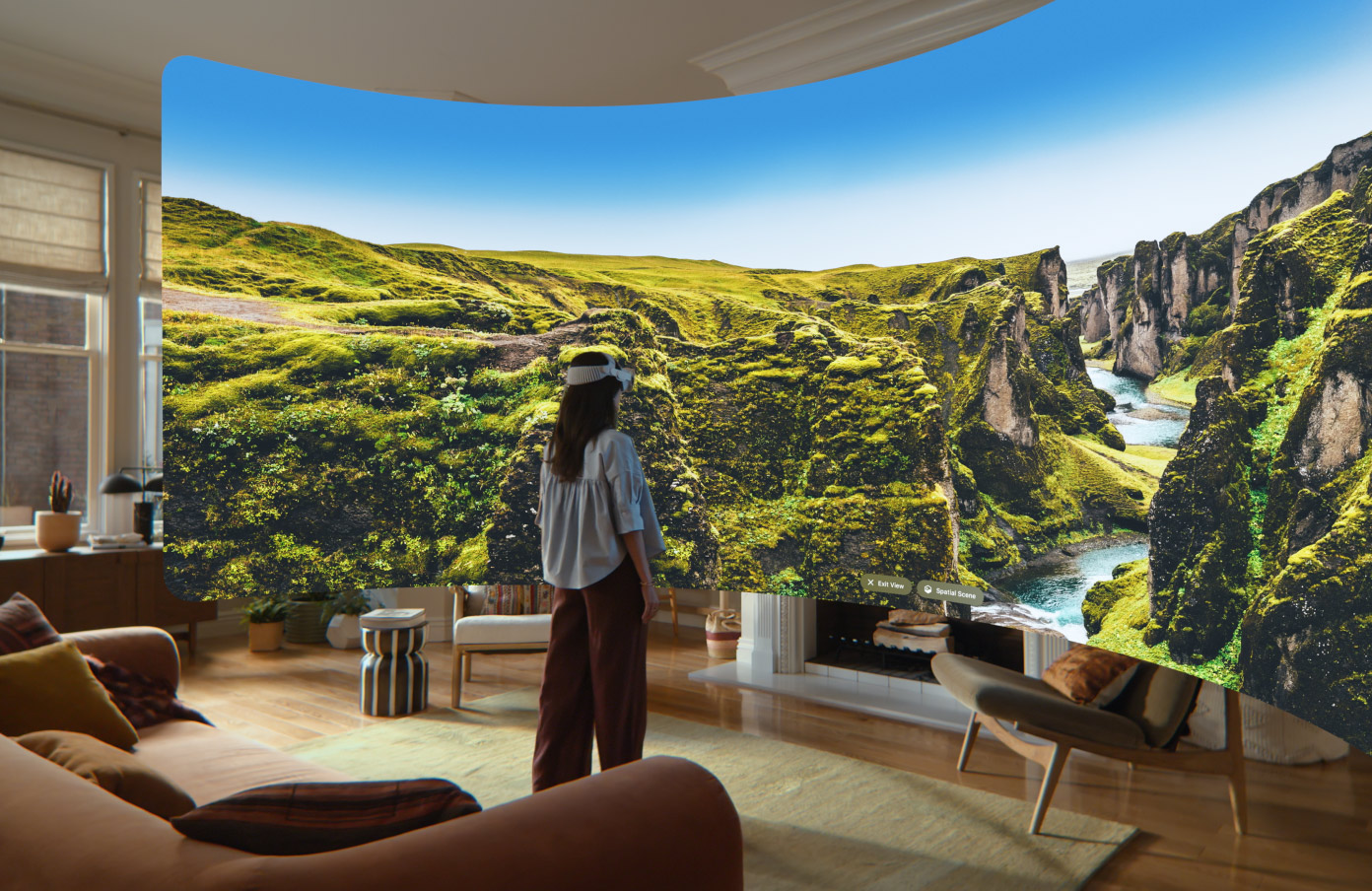 Az Apple Vision Pro nézete látható, amelyen egy panorámakép jelenik meg sziklás, zöldellő sziklafalakkal, köztük egy patakkal, valamint a távolba nyúló kék égbolttal.