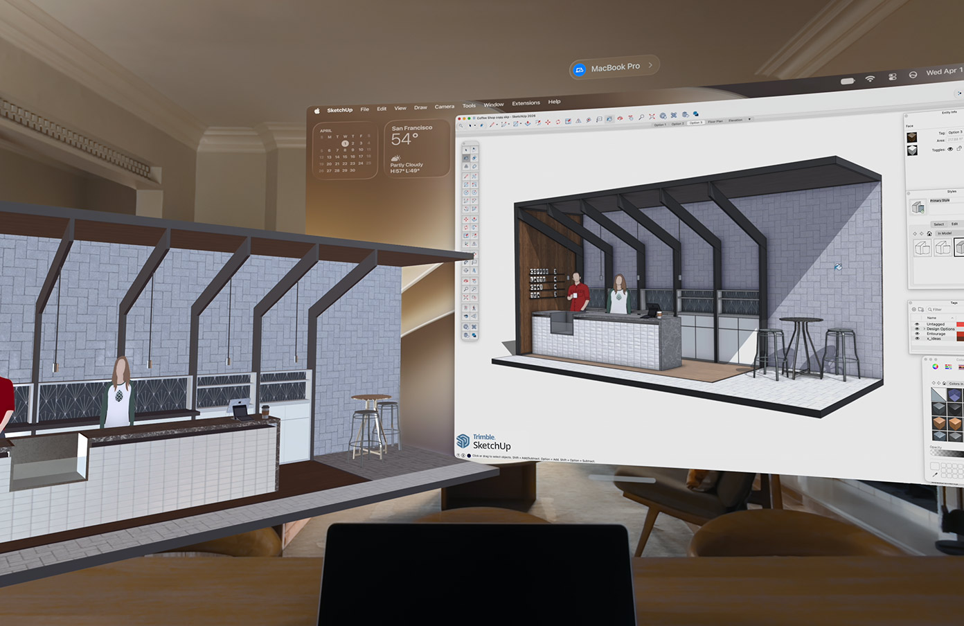 A Vision Pro-n egy MacBook Pro kijelzőjének tartalma látható egy felületen, mellette pedig egy kávézó kiszolgálópultját ábrázoló 3D-modell jelenik meg, két mögötte álló emberrel.